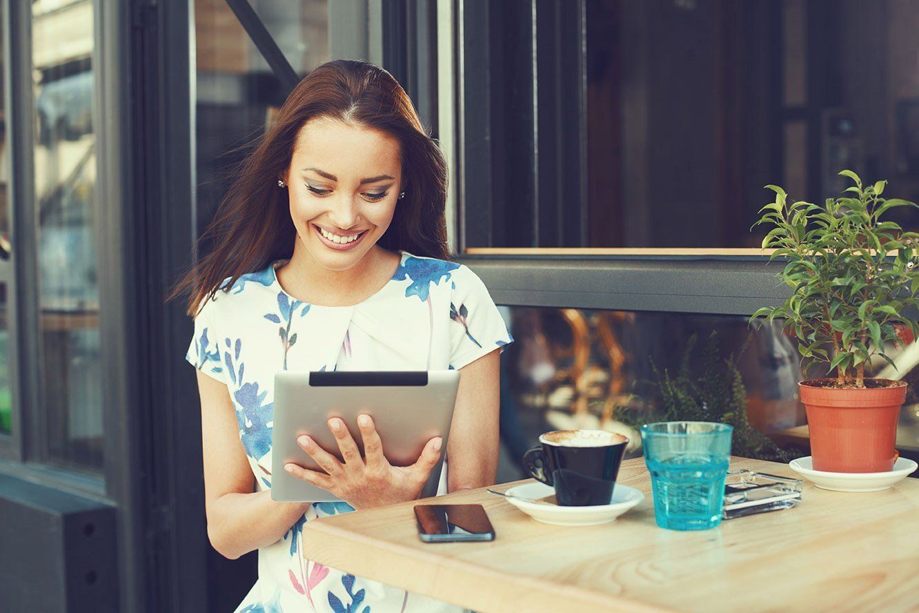 A woman is sitting at a table using a tablet computer.