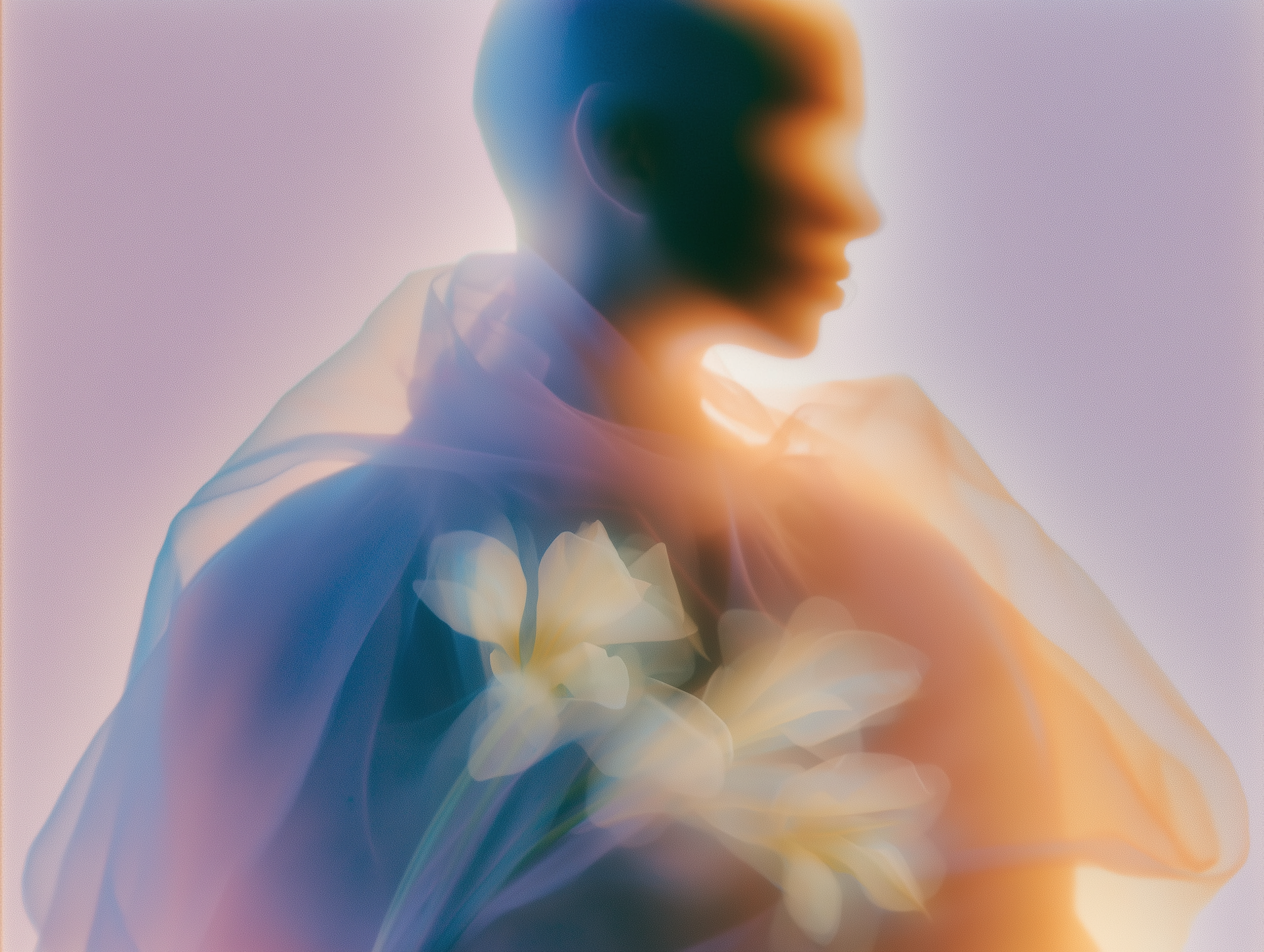 Abstract blurred portrait with translucent blue and orange fabric and pale flowers on the chest