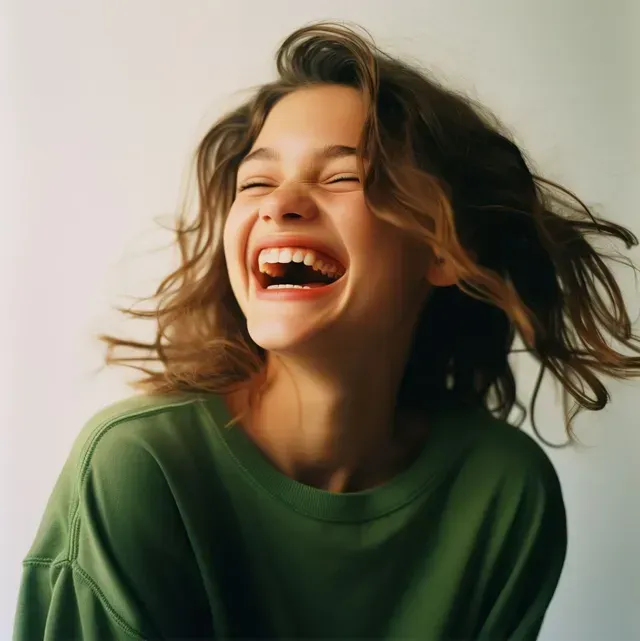 A woman in a green shirt is laughing with her mouth open