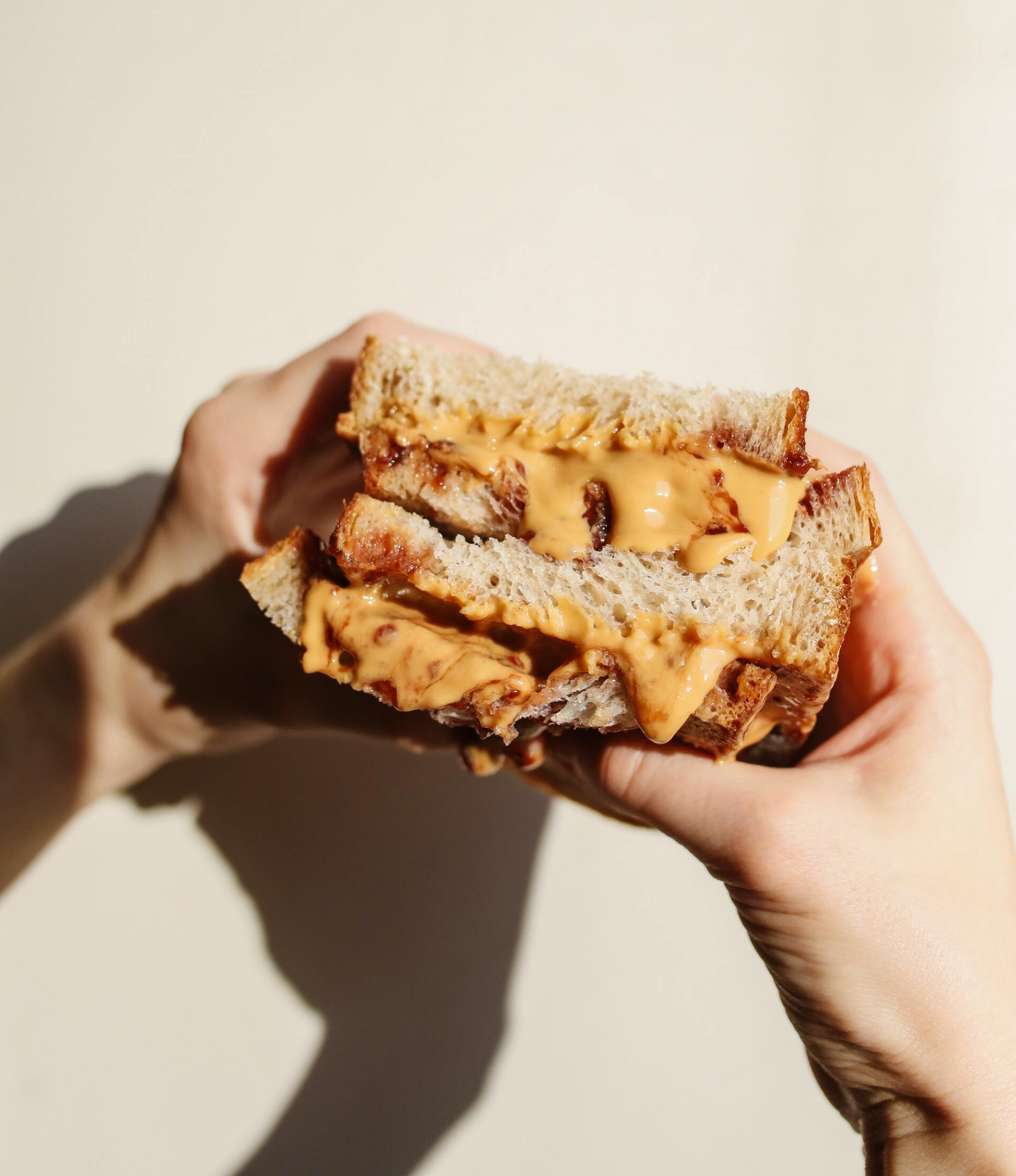 A person is holding a peanut butter sandwich in their hands
