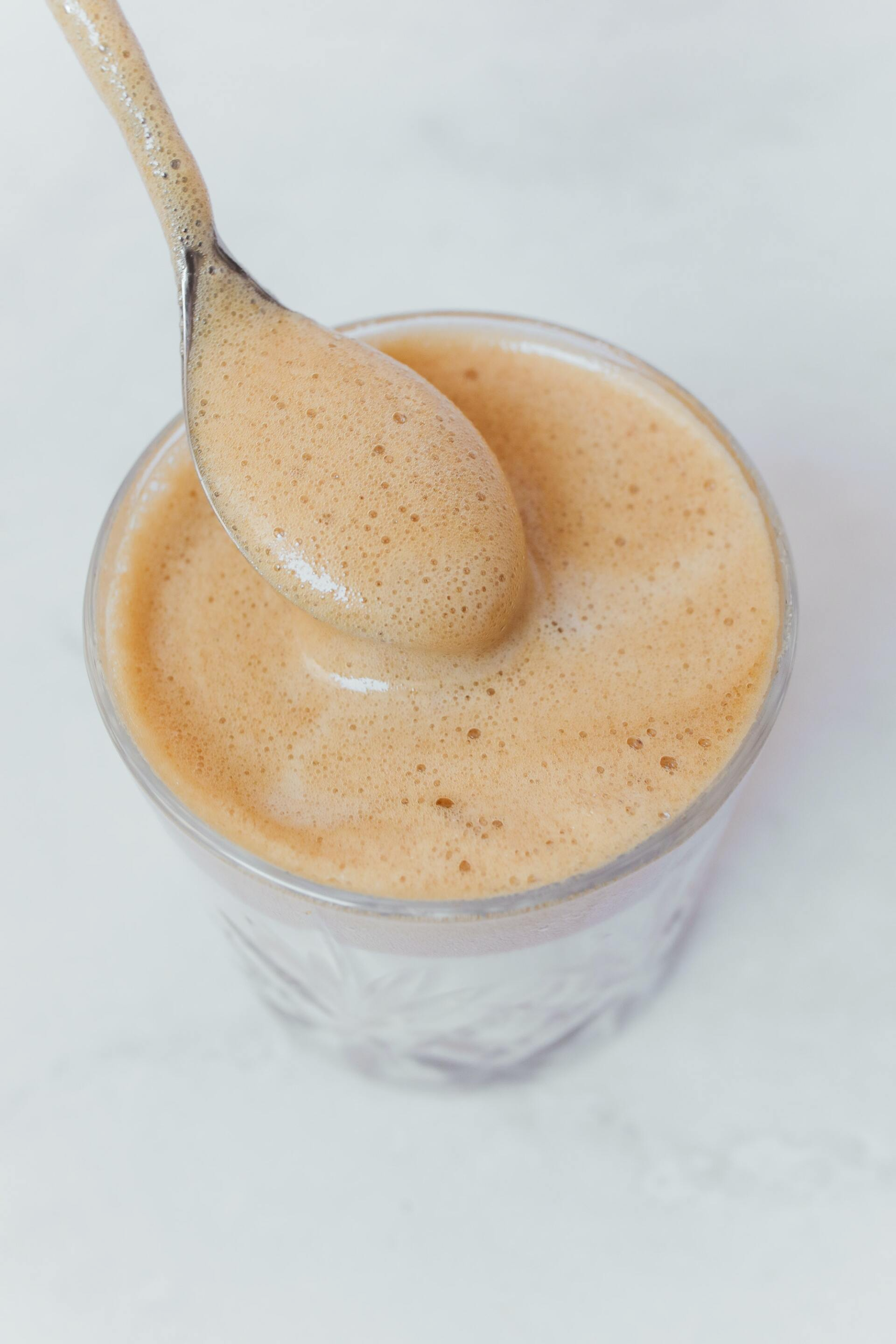 A spoon is sticking out of a glass of coffee.