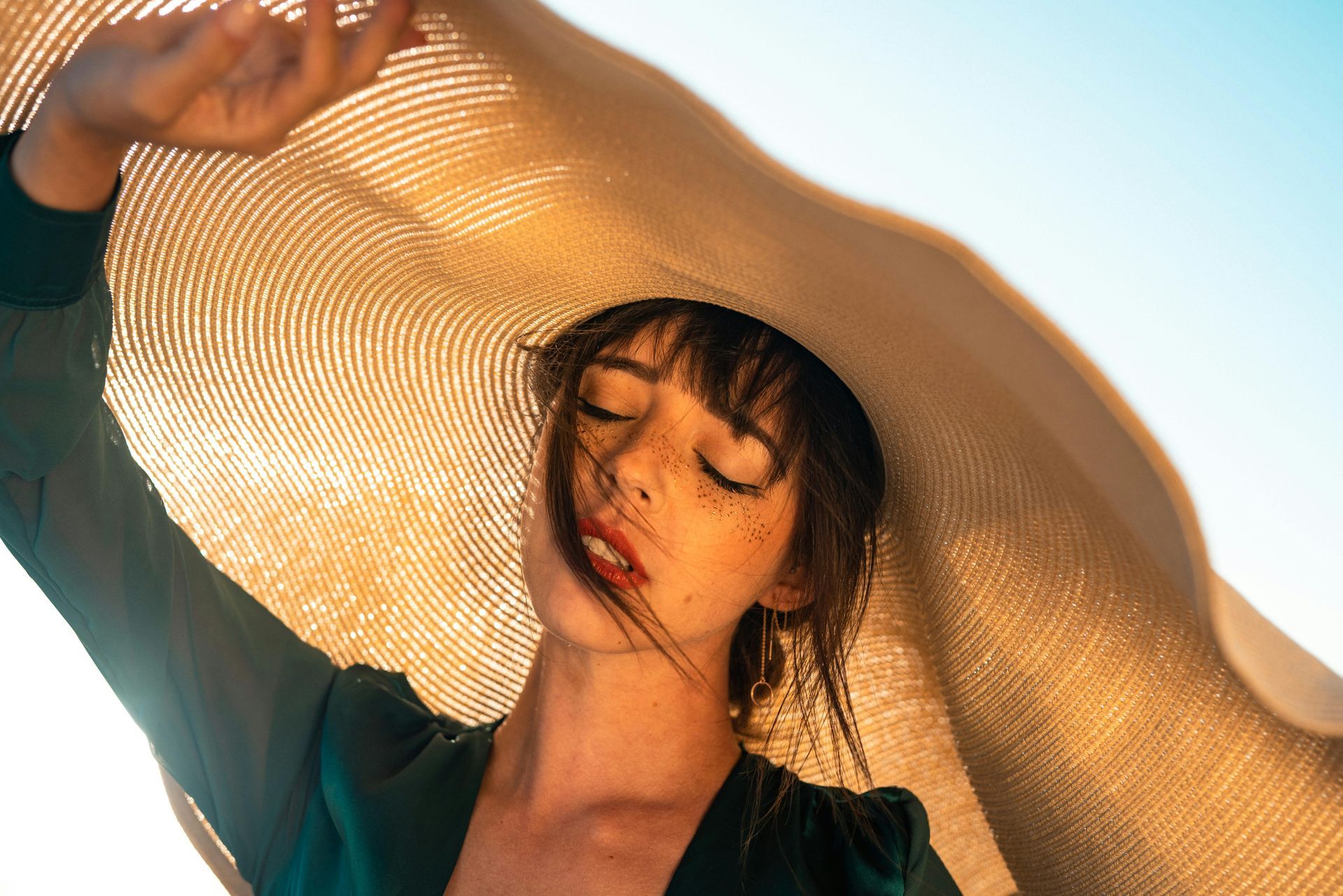 A woman wearing a large hat with her eyes closed.