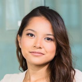 Woman with brown hair, smiling, in a well-lit indoor setting.