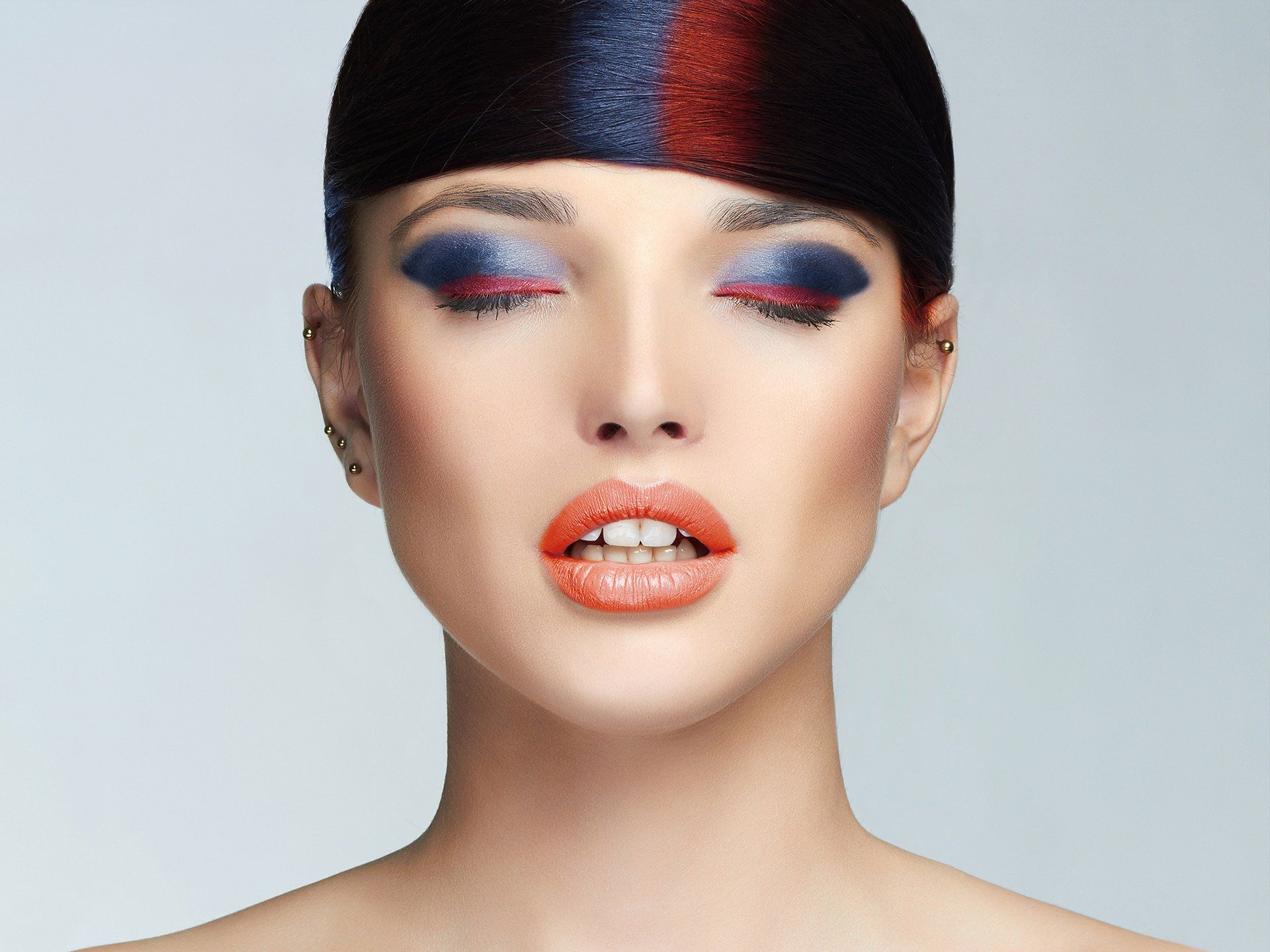 A woman with vibrant makeup featuring blue and red eye shadow, promoting Mokara Solutions, Hair and Skin Wellness.