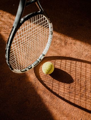 A tennis racket and ball are on a tennis court.