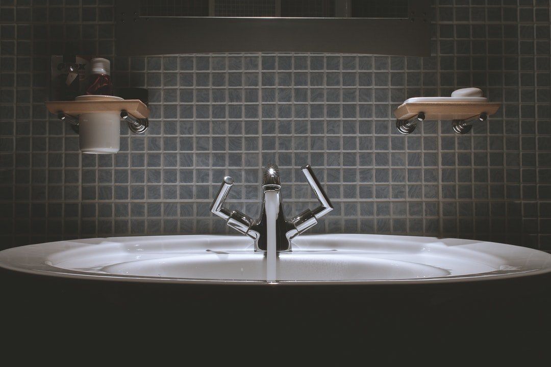 A bathroom sink with a faucet and shelves on the wall.