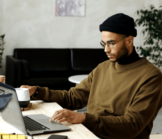 Un hombre está sentado en un escritorio usando una computadora portátil.