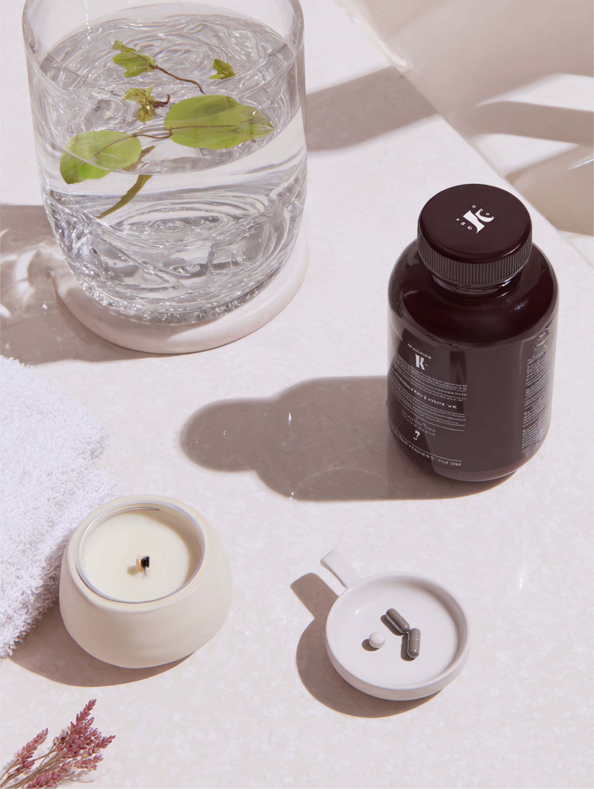 Glass of water with greens, supplements, candle, towel, setting.