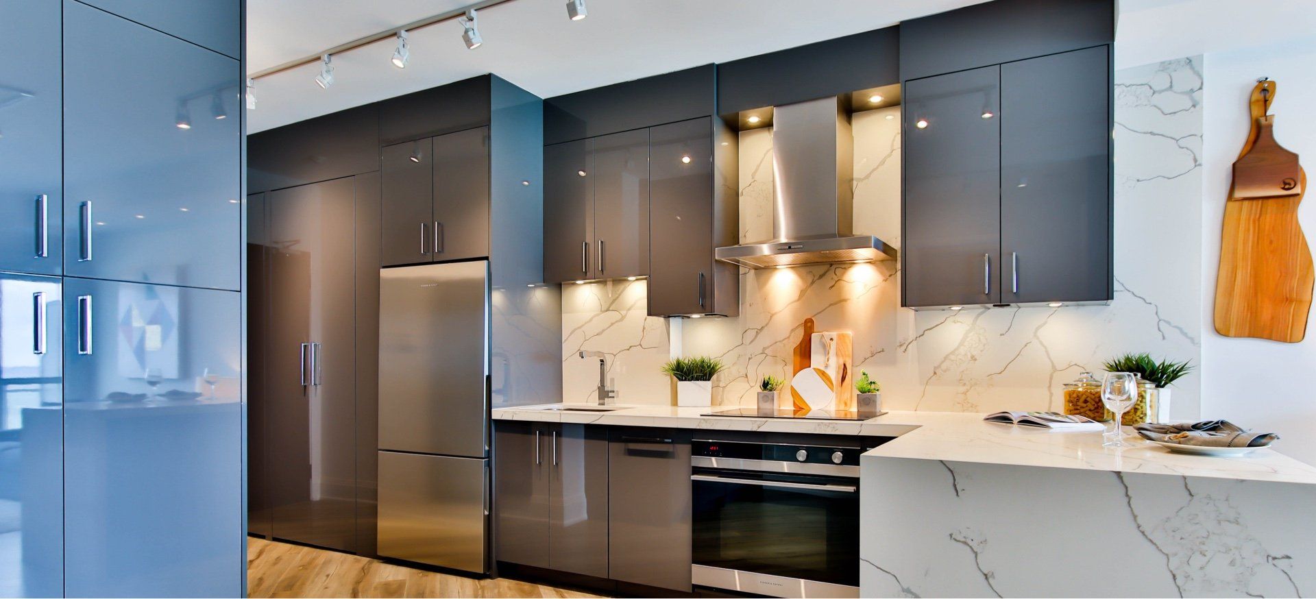 Modern kitchen with gray cabinets, stainless steel appliances, and white countertops.
