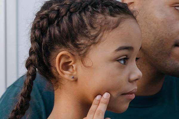 a young girl touching her cheek