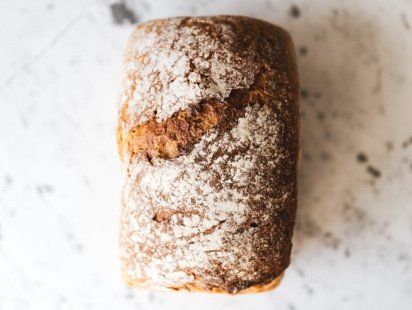 A loaf of bread with powdered sugar on it is sitting on a table.