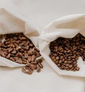 Two bags filled with coffee beans on a table