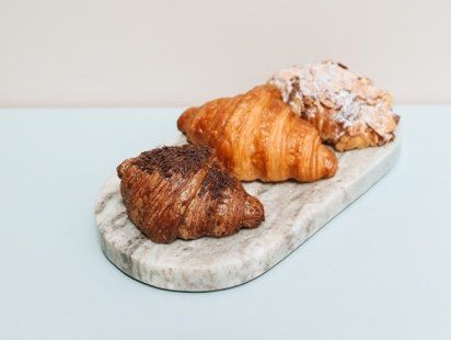 Three croissants are sitting on a marble cutting board.