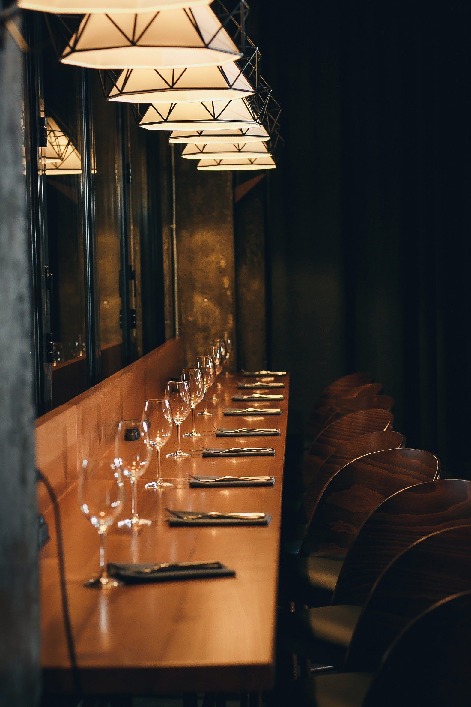 A long wooden table with glasses of wine on it in a restaurant.