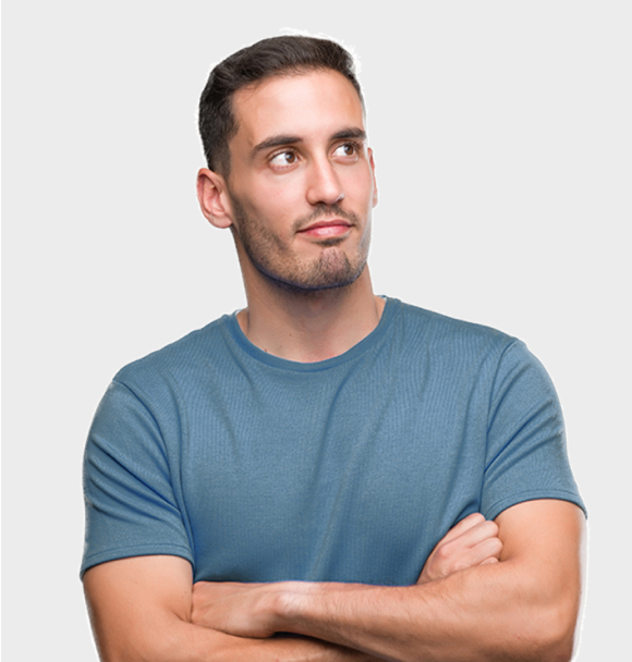 A man in a blue shirt is standing with his arms crossed and looking up.