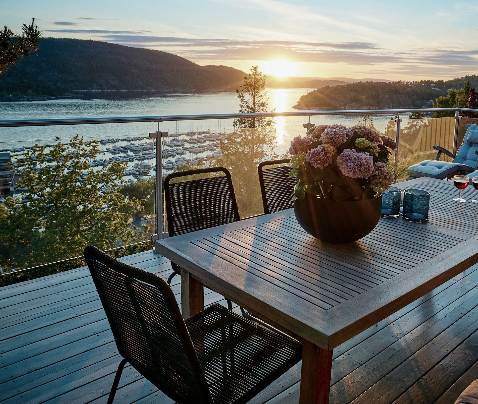 A table with a vase of flowers on it on a deck overlooking a body of water