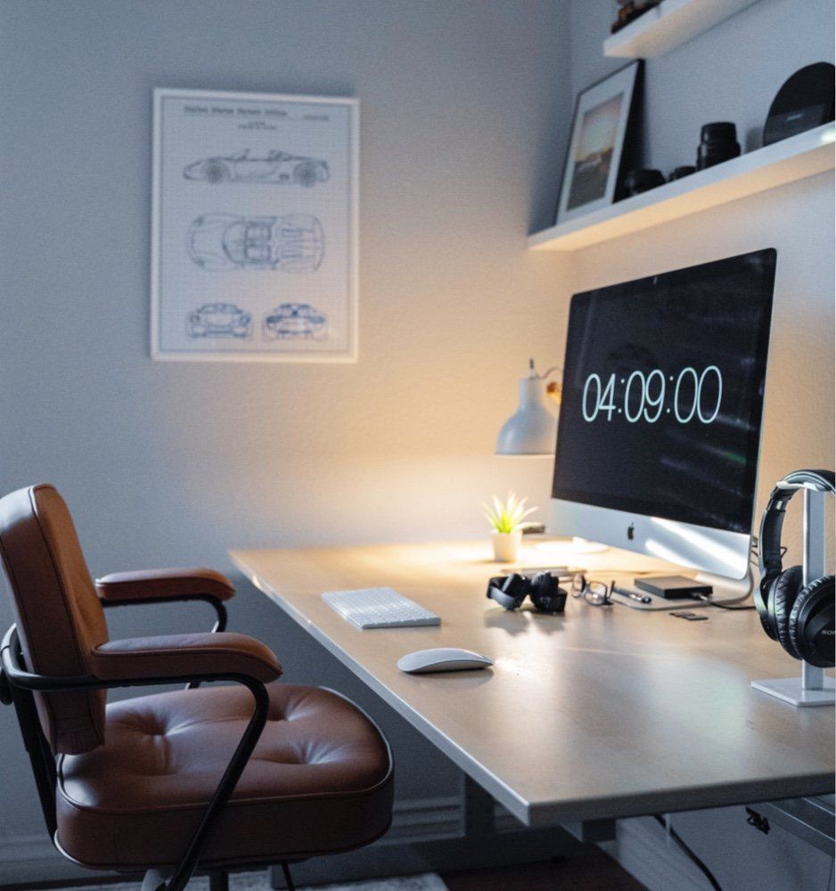 computer monitor on a small desk with a tan leather desk chair