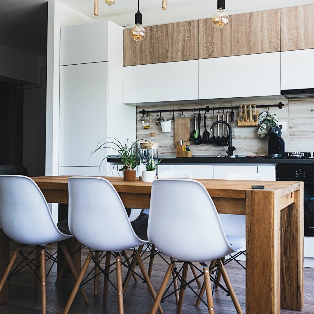 A kitchen with a wooden table and white chairs