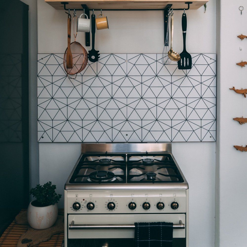 A kitchen with a stove and utensils hanging on the wall