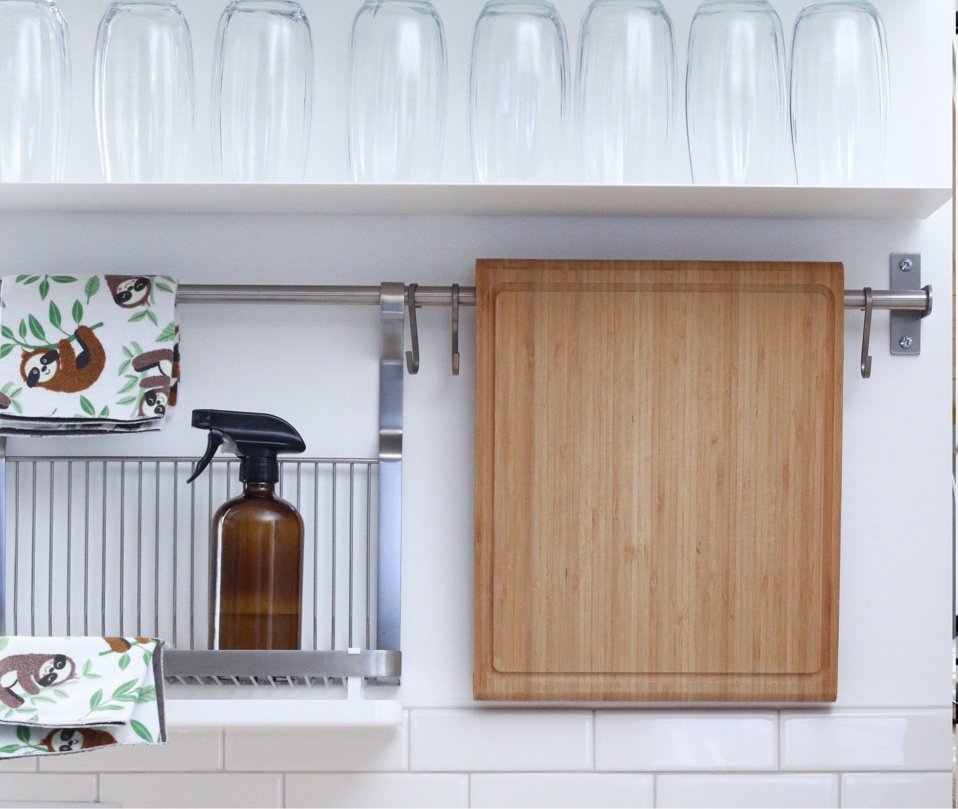 A kitchen with a cutting board and glasses on a shelf