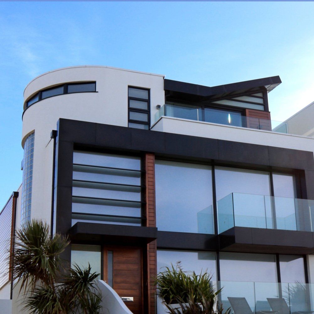 A modern house with a balcony and a blue sky in the background