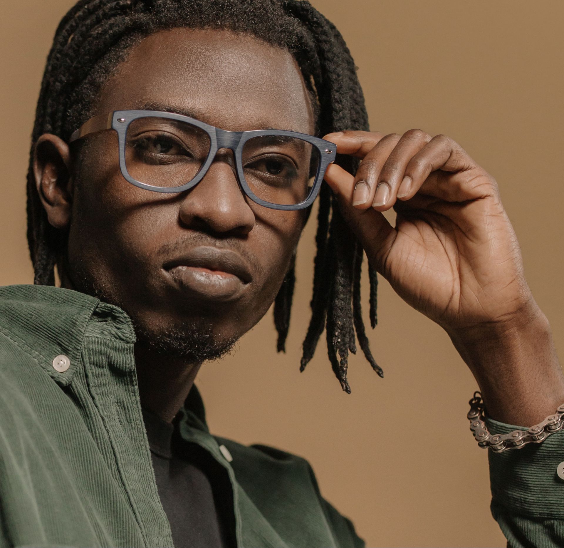 A man with dreadlocks wearing glasses and a green shirt
