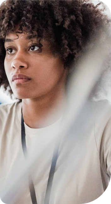 A woman with curly hair is wearing a lanyard around her neck.