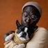 A man is holding a black and white dog in his arms.