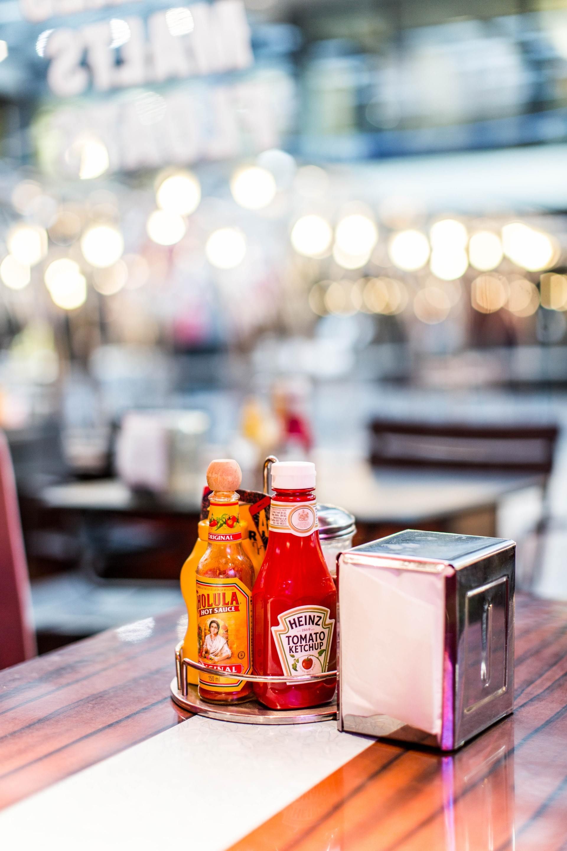 A bottle of ketchup and mustard are on a table in a restaurant.