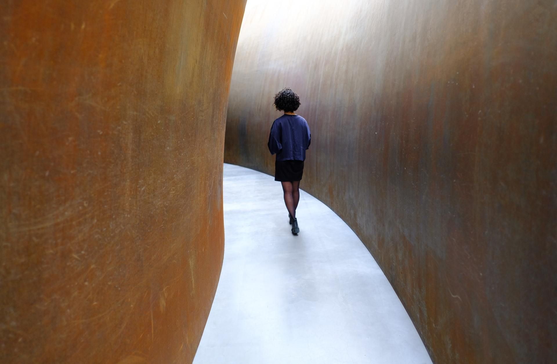 A woman is walking through a narrow tunnel.