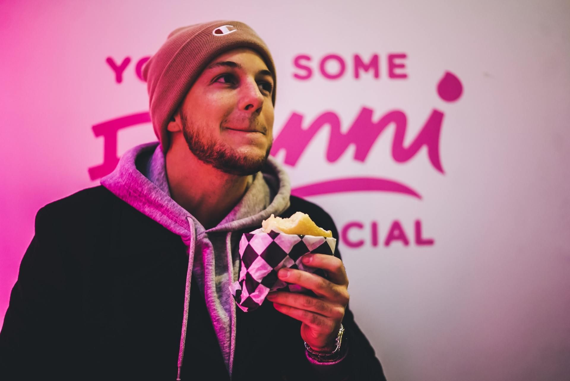 A man is eating a sandwich in front of a sign that says some jenny special