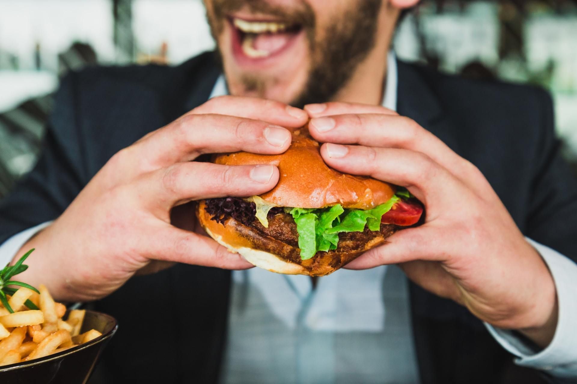 A man is eating a hamburger and french fries at a restaurant.