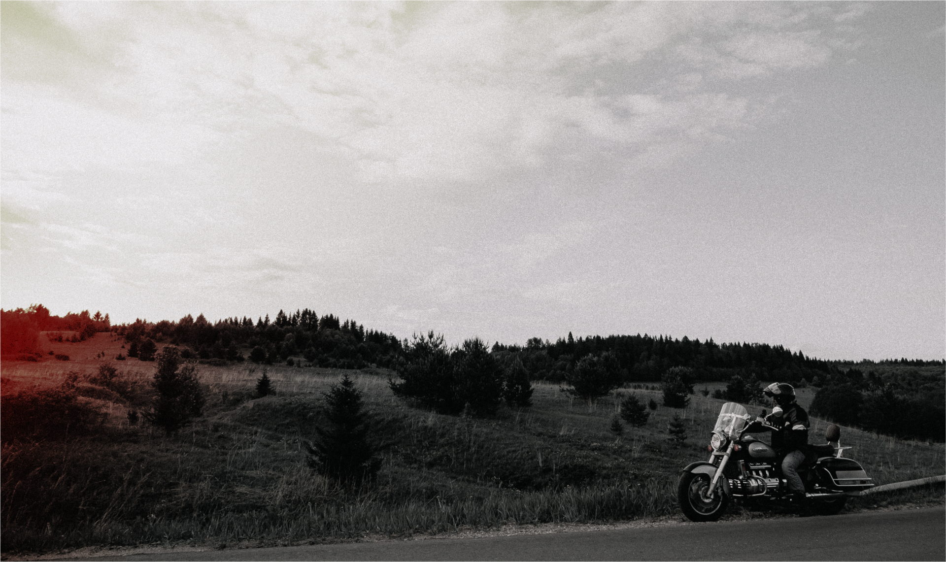 A man is riding a motorcycle down a country road.
