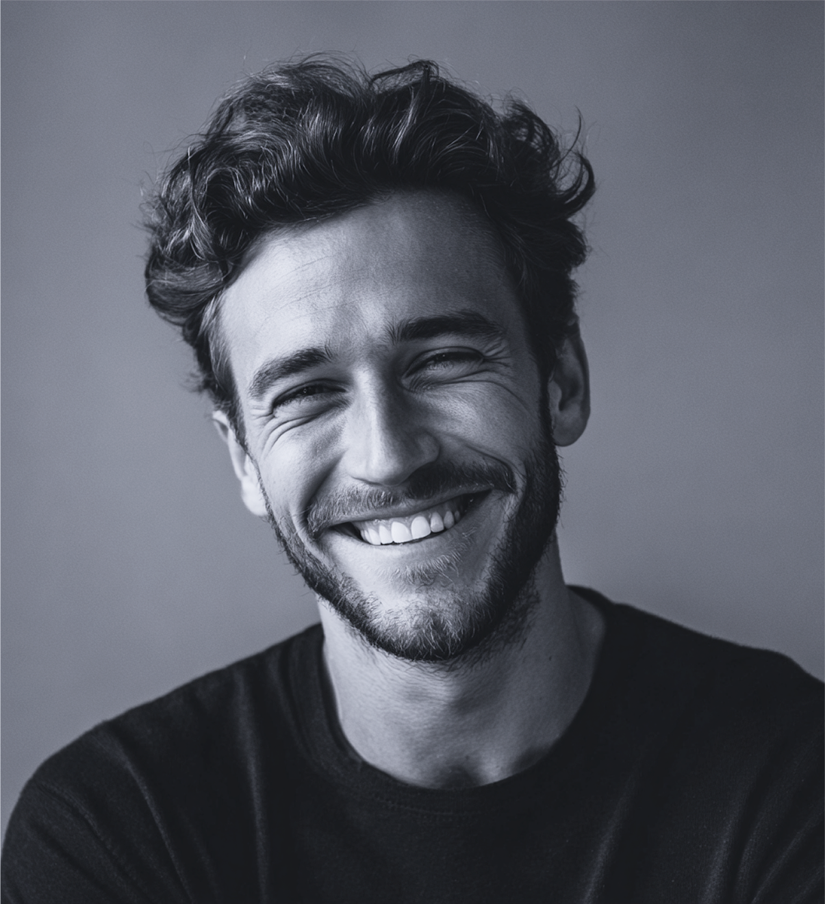 Man with curly hair smiling widely. Black and white photograph.