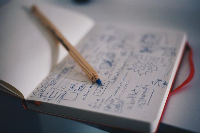 A pencil is sitting on top of a notebook on a table.