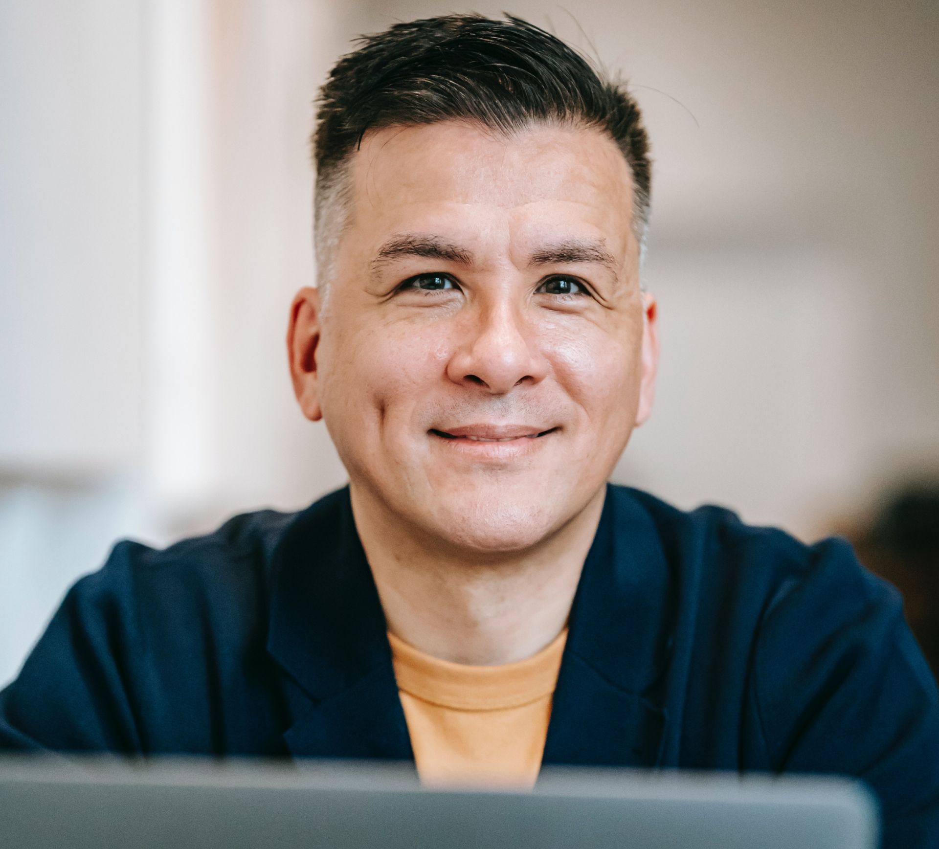 A man is smiling while sitting in front of a laptop computer.
