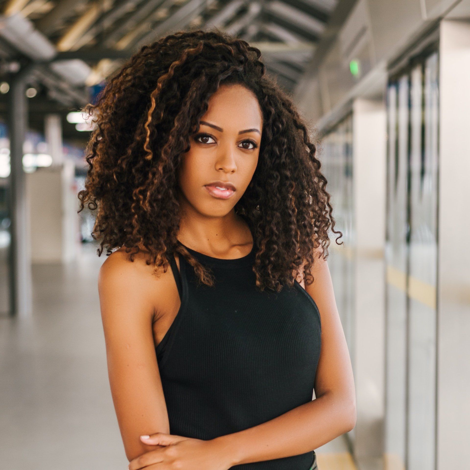 A woman with curly hair is wearing a black tank top.