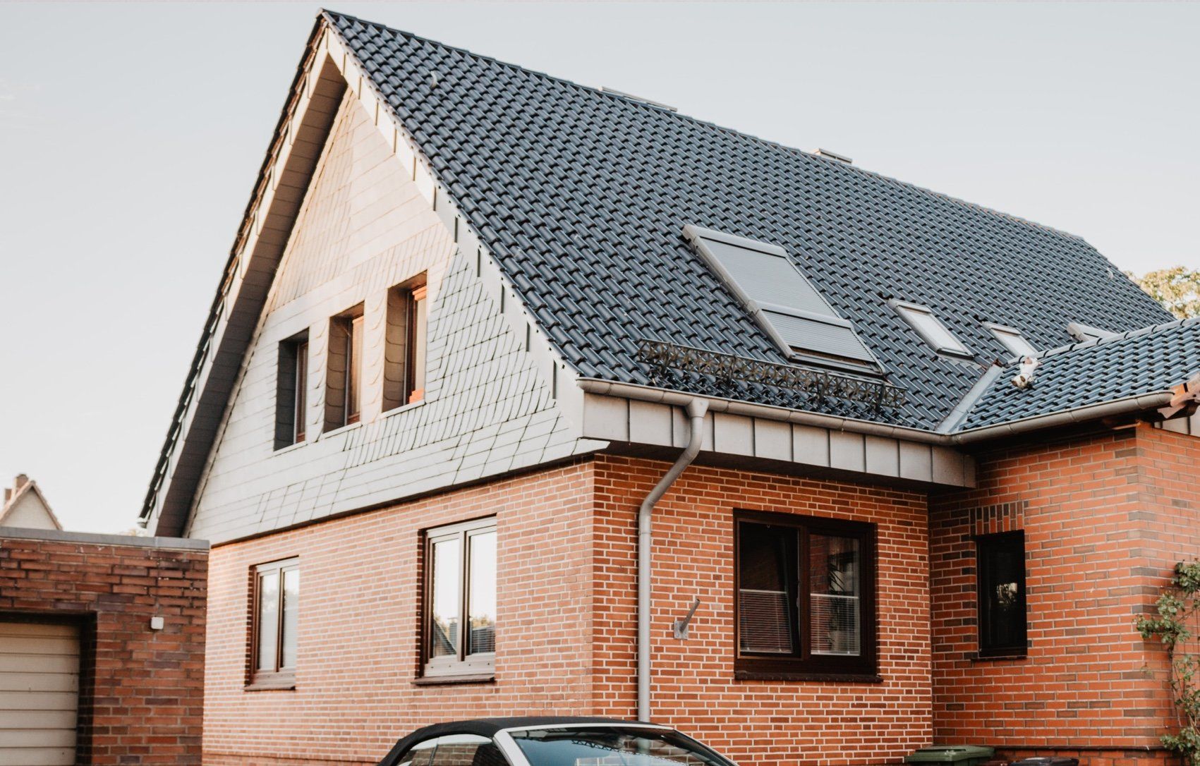 Une maison en briques avec une voiture garée devant