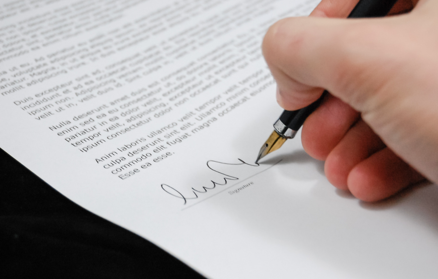 Hand signing a document with a fountain pen.