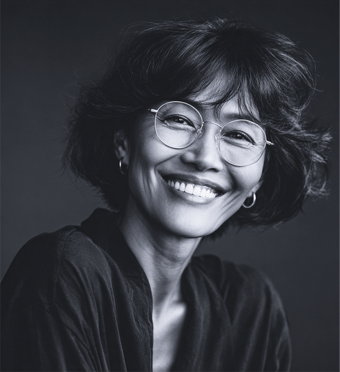 Smiling woman with glasses, dark hair, wearing a dark shirt. Black and white photo.