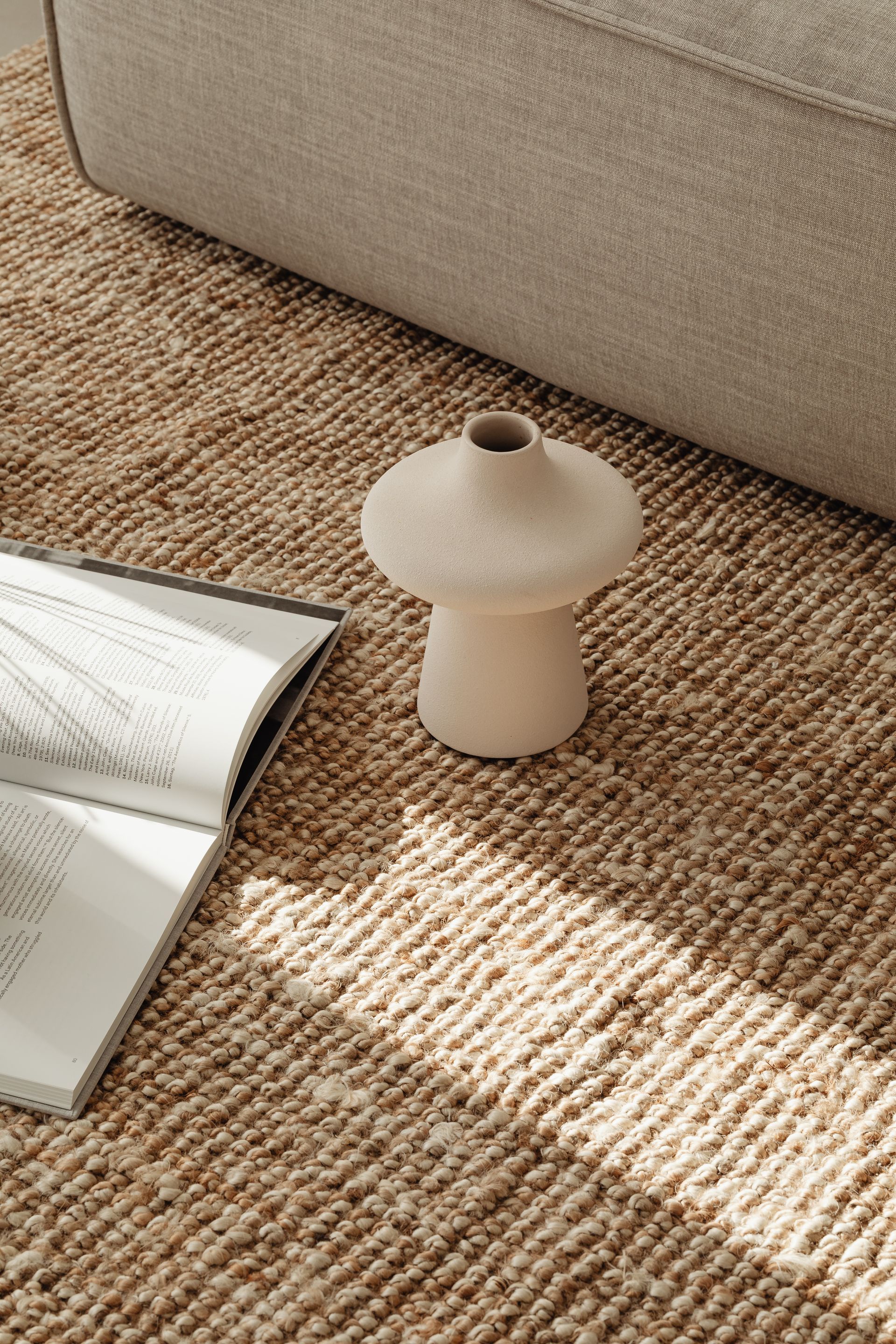 A vase is sitting on a rug next to a book.