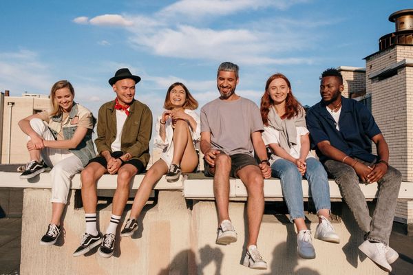 a group of people are sitting on a stone ledge on a building