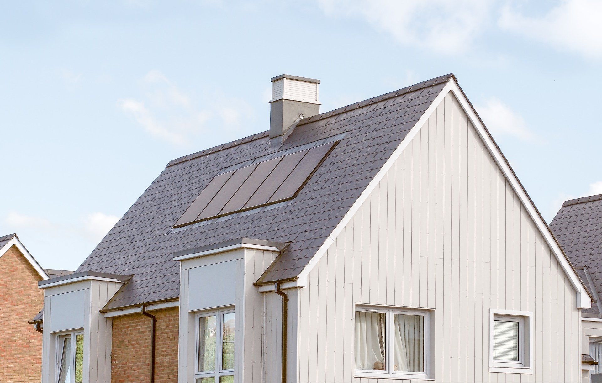 Een wit huis met een bruin dak en een schoorsteen