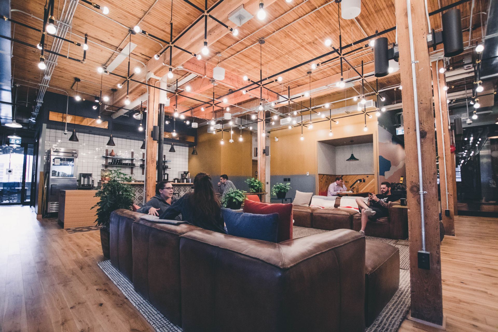 A group of people are sitting on couches in a large wooden room.