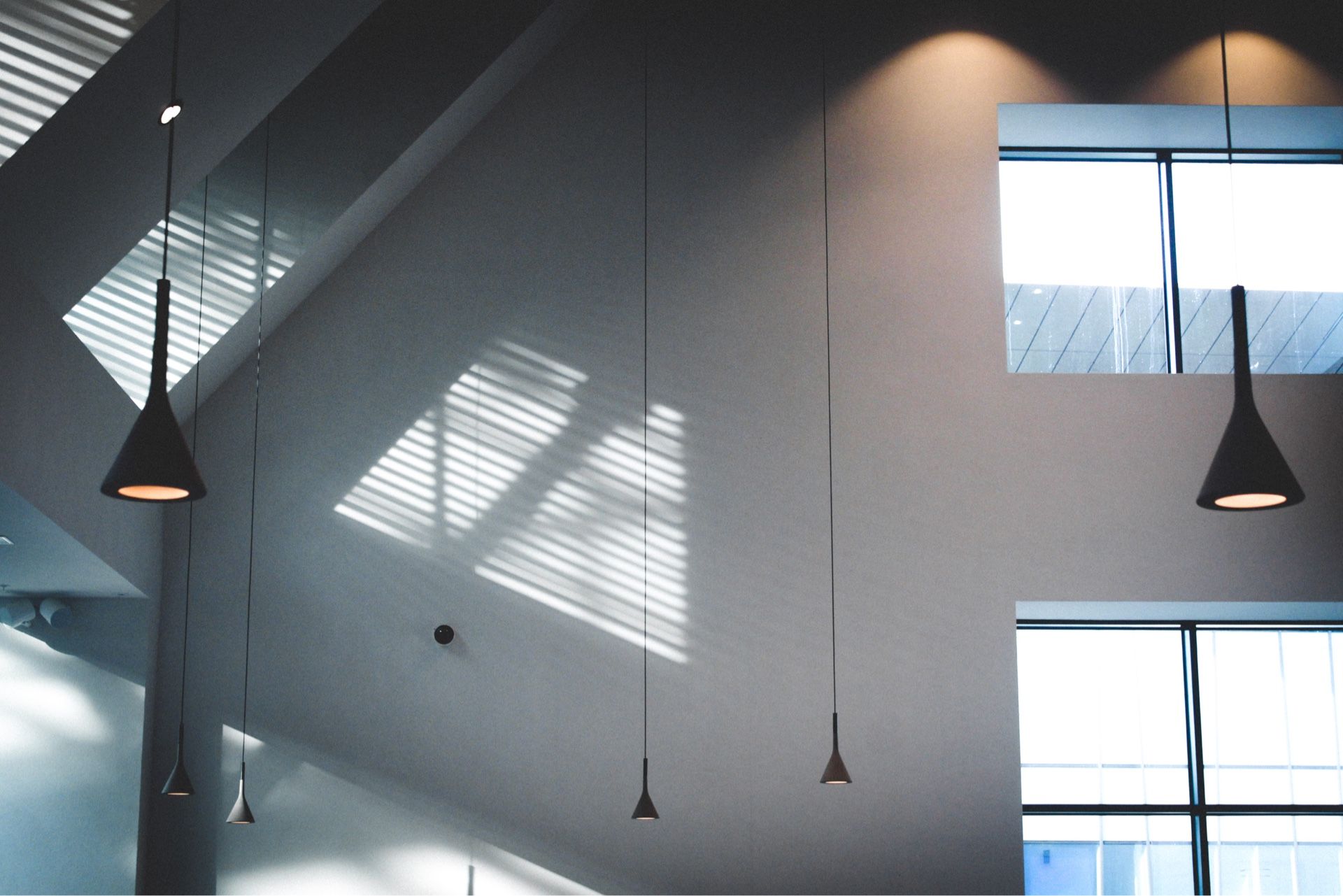 Modern interior with pendant lights, shadows from window blinds.