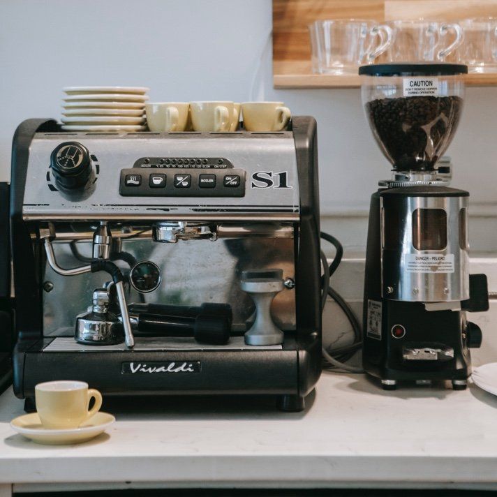 A vivaldi coffee machine sits on a counter next to a coffee grinder