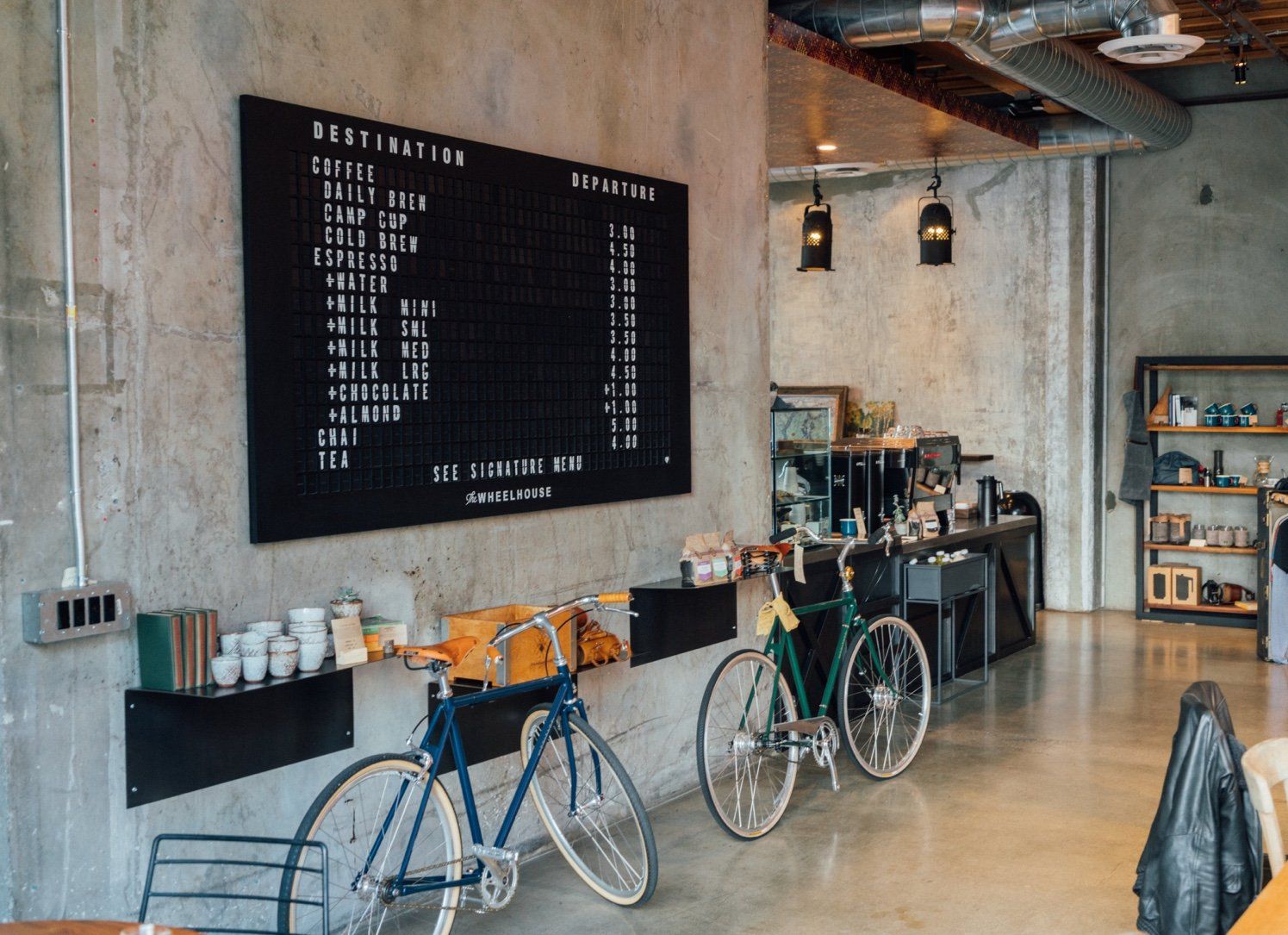 Two bicycles are parked in front of a sign on the wall.