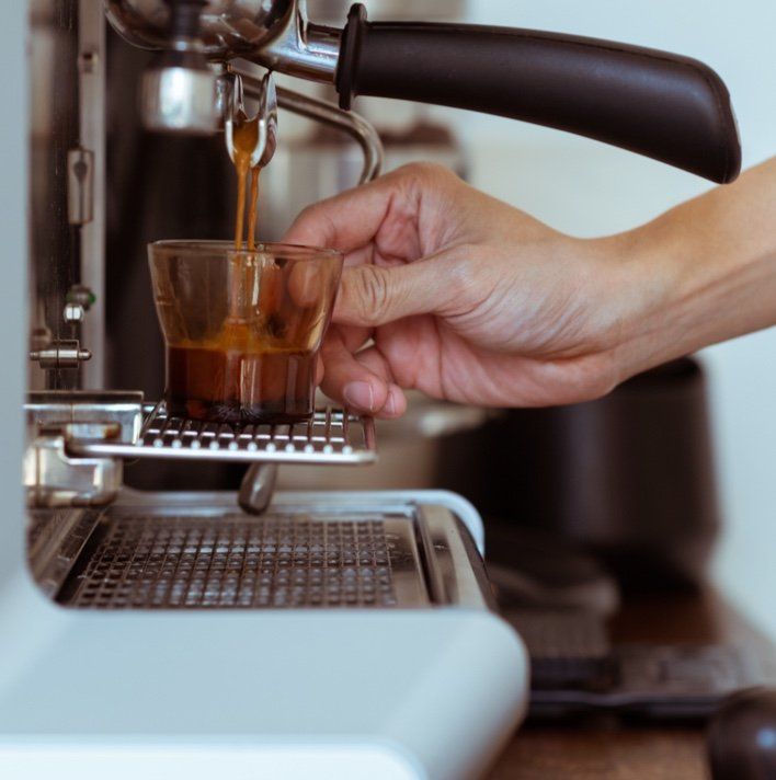A person is pouring coffee into a shot glass