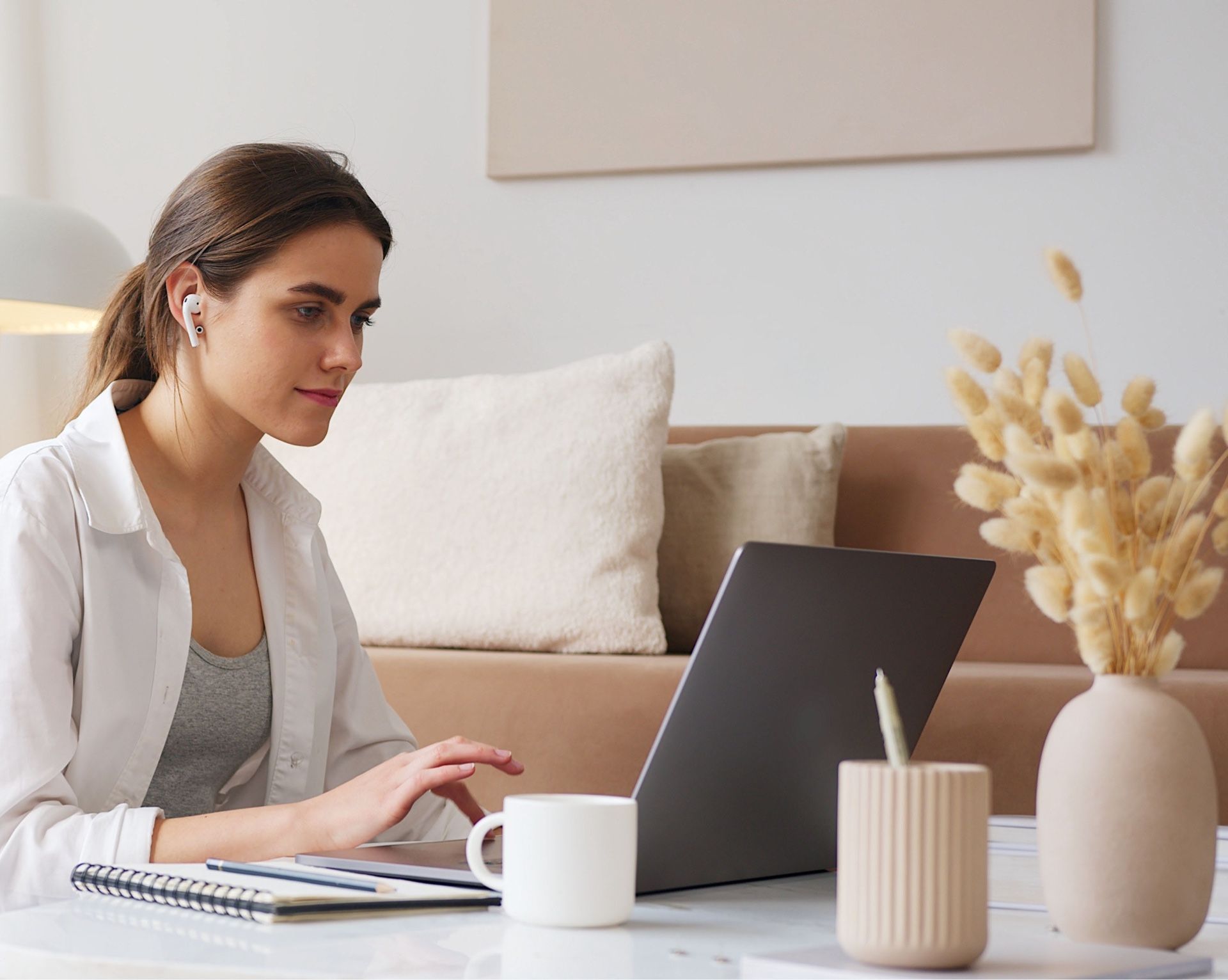A woman is sitting at a table using a laptop computer.