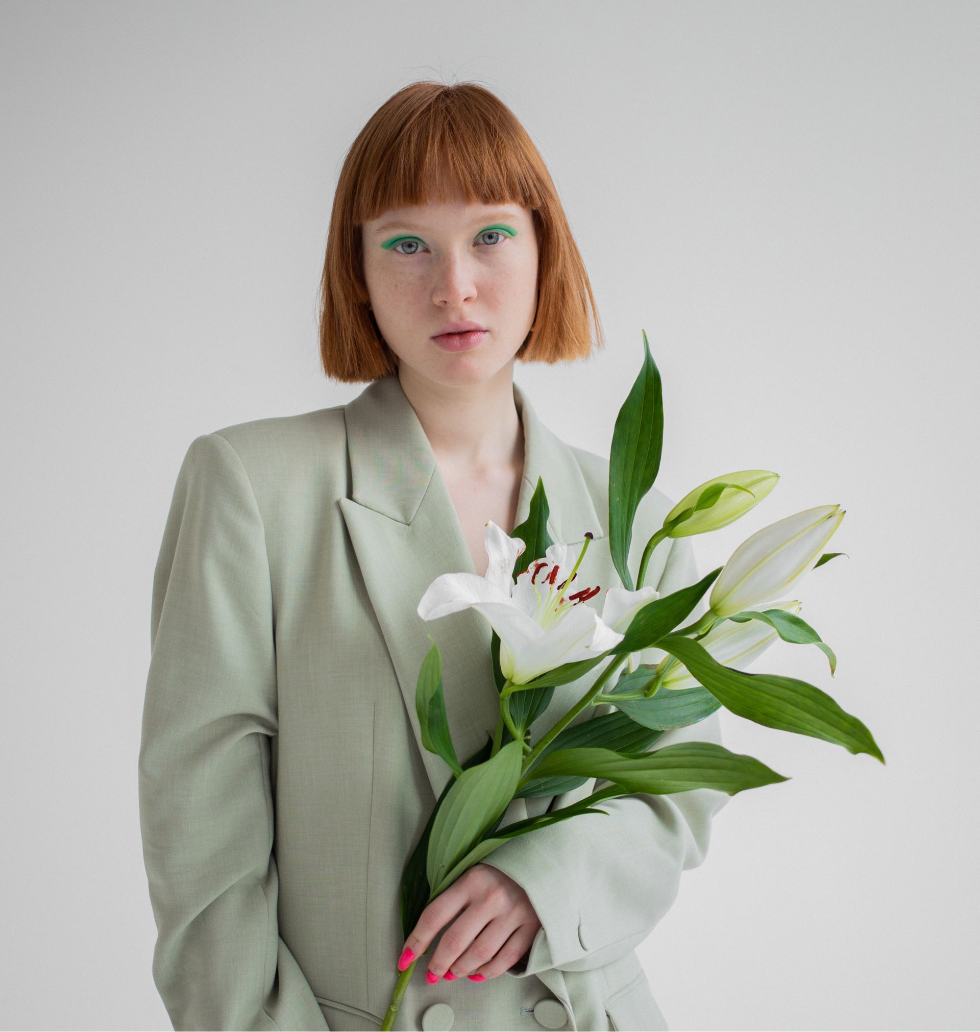 A woman in a green jacket is holding a bouquet of flowers